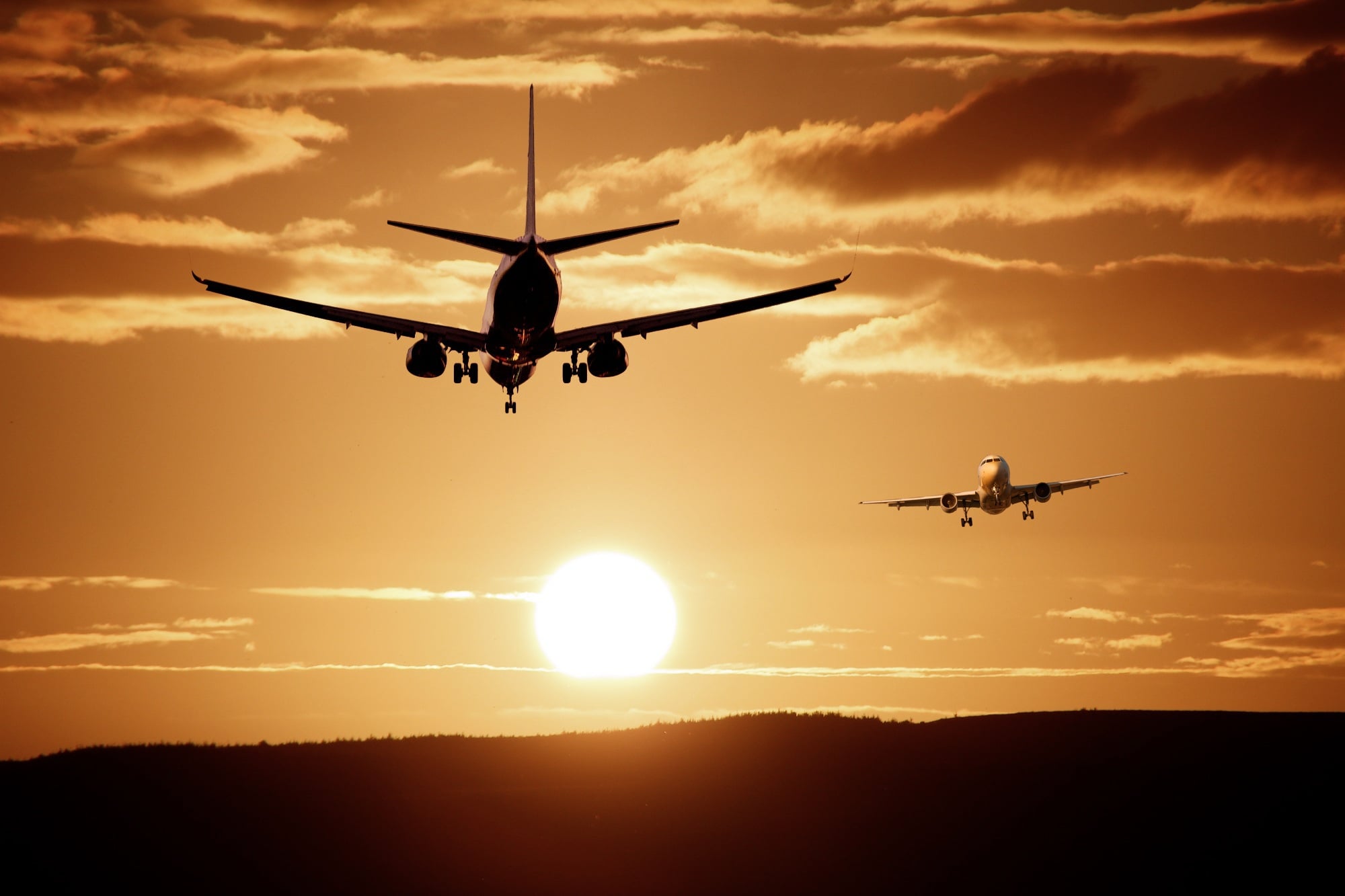 Airplanes flying above the horizon at sunset